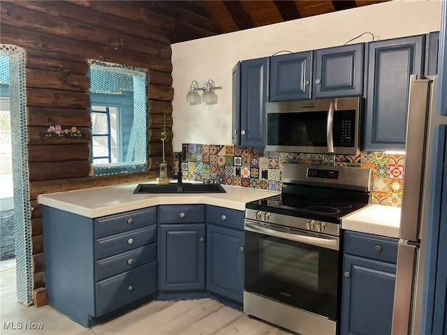 kitchen featuring blue cabinetry, stainless steel appliances, log walls, and sink