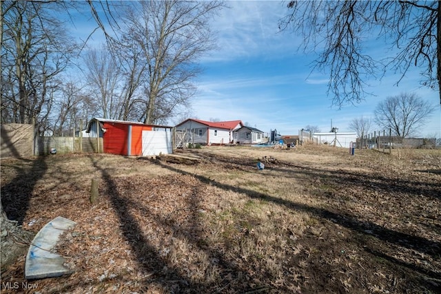 view of yard featuring an outbuilding, a storage unit, fence, and a garage