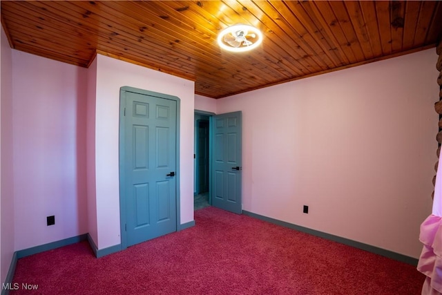 unfurnished bedroom featuring ornamental molding, carpet, wood ceiling, and baseboards