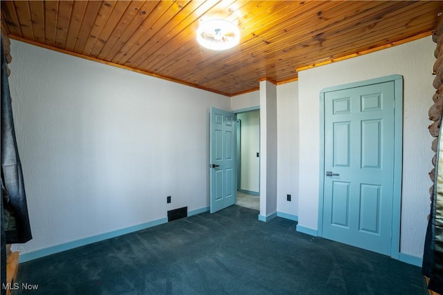 unfurnished bedroom featuring baseboards, visible vents, wood ceiling, dark colored carpet, and crown molding