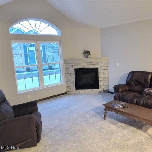 living room featuring lofted ceiling, a brick fireplace, and carpet floors