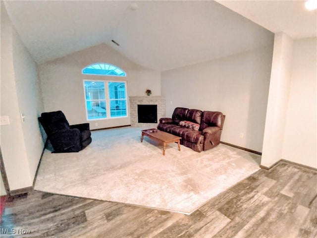 living room with a fireplace, vaulted ceiling, and hardwood / wood-style floors