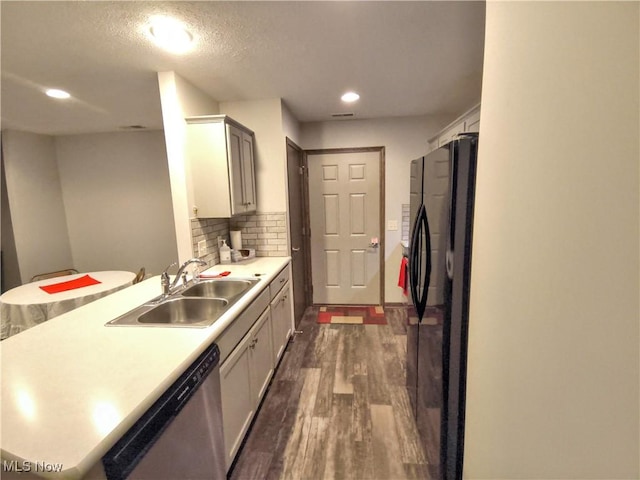 kitchen with dark wood-type flooring, sink, black fridge, tasteful backsplash, and stainless steel dishwasher