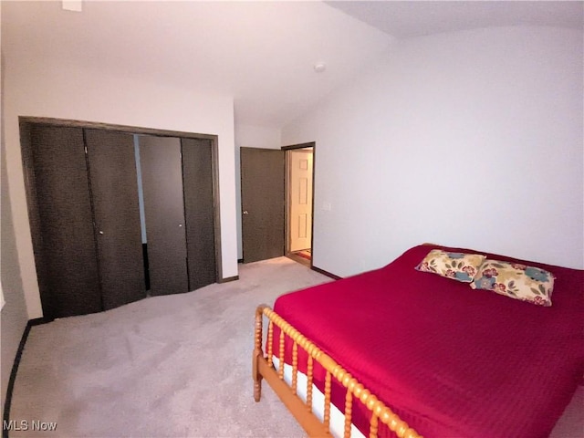 bedroom with lofted ceiling, light colored carpet, and a closet