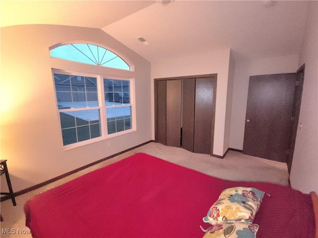 bedroom featuring lofted ceiling, a closet, and carpet flooring