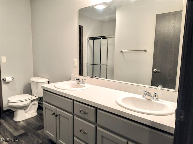 bathroom featuring vanity, wood-type flooring, a shower with door, and toilet