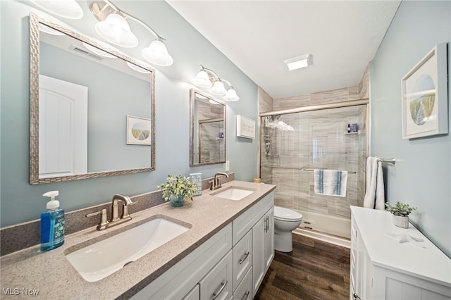 bathroom with wood-type flooring, toilet, a shower with door, and vanity