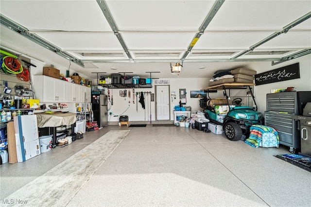 garage featuring a garage door opener, stainless steel fridge, and a workshop area