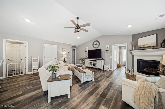 living room featuring dark wood-type flooring, vaulted ceiling, and ceiling fan