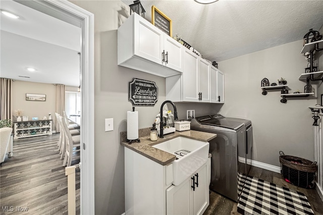 clothes washing area with sink, cabinets, a textured ceiling, dark hardwood / wood-style floors, and independent washer and dryer