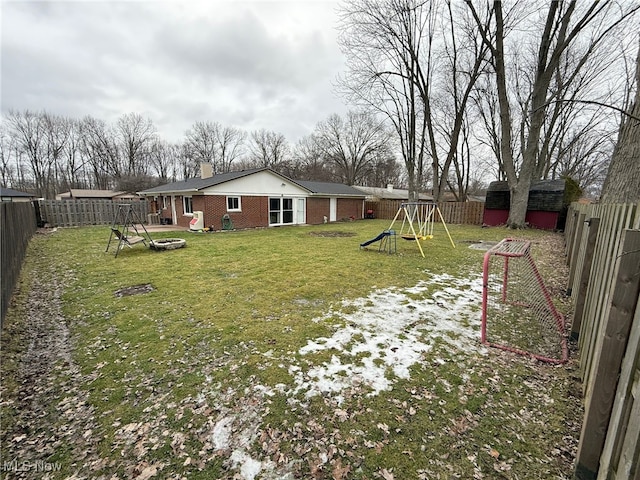 view of yard featuring a playground, a shed, and a fire pit