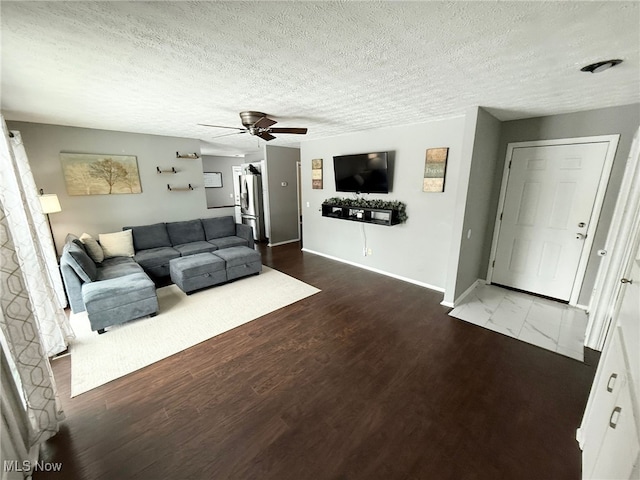 living room with a textured ceiling, dark hardwood / wood-style floors, and ceiling fan