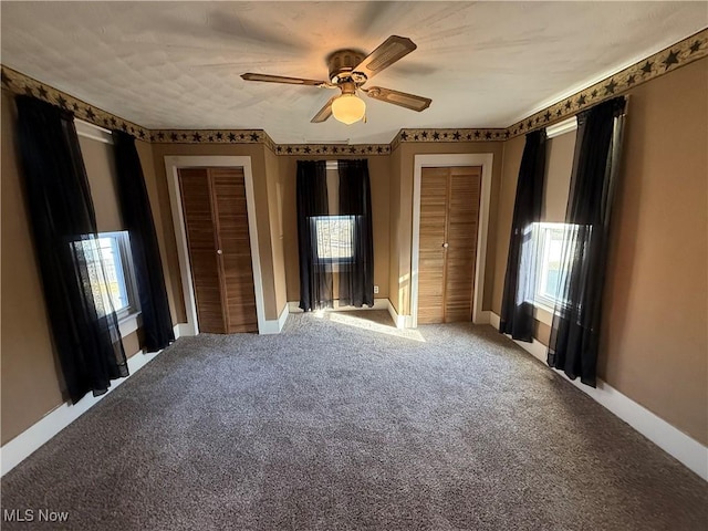 unfurnished bedroom featuring carpet flooring, two closets, and ceiling fan