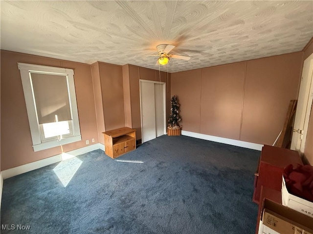 interior space with ceiling fan, a textured ceiling, and dark colored carpet