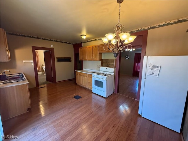 kitchen featuring white appliances, decorative light fixtures, hardwood / wood-style floors, and a notable chandelier