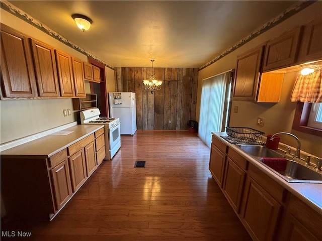 kitchen featuring sink, a chandelier, dark hardwood / wood-style flooring, pendant lighting, and white appliances