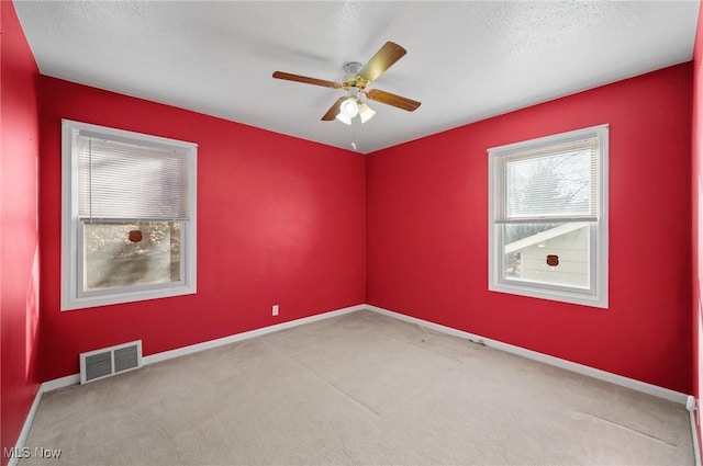 carpeted spare room with ceiling fan and a textured ceiling