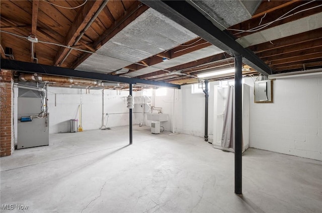 basement with electric panel, sink, and heating unit