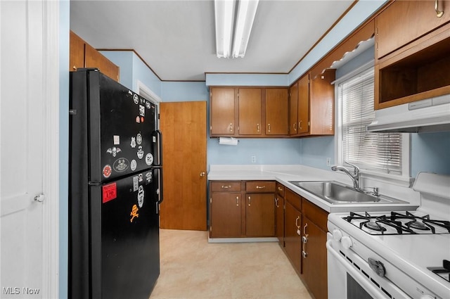 kitchen featuring sink, black refrigerator, and white gas stove