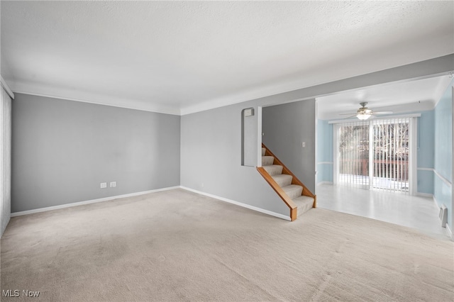 carpeted empty room featuring ceiling fan and a textured ceiling