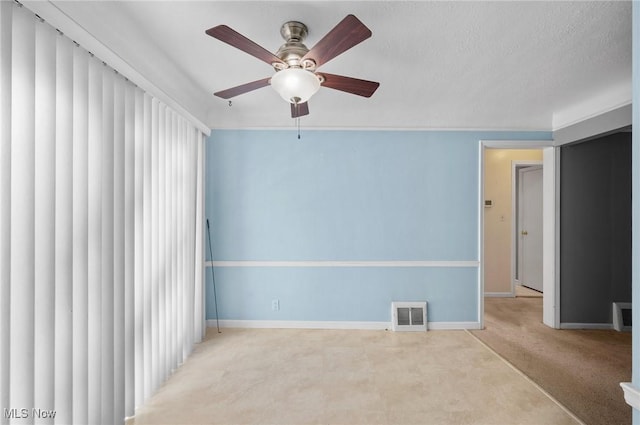 unfurnished room with ceiling fan, light colored carpet, and a textured ceiling