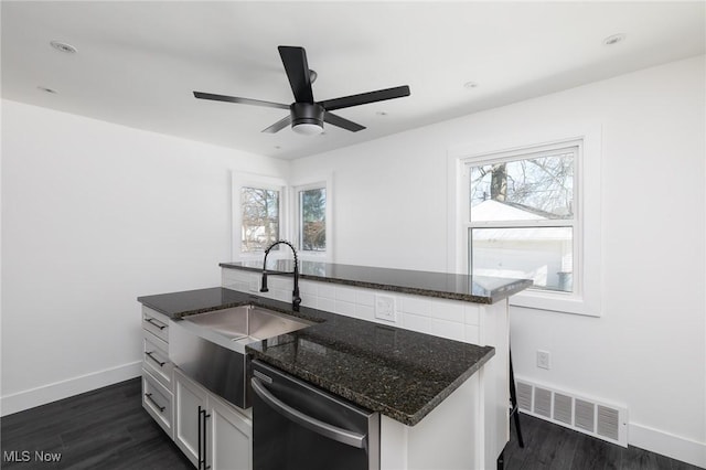 kitchen featuring white cabinetry, a healthy amount of sunlight, dark stone countertops, and dishwasher