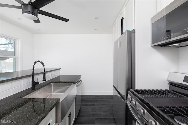 kitchen with white cabinetry, backsplash, dark stone counters, and appliances with stainless steel finishes