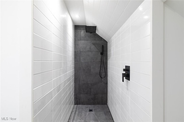 bathroom with lofted ceiling, tile patterned floors, tile walls, and a shower