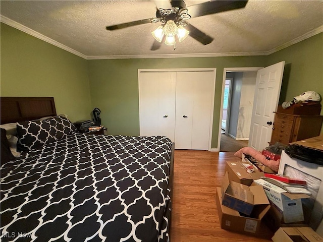 bedroom featuring hardwood / wood-style floors, ornamental molding, a closet, and a textured ceiling