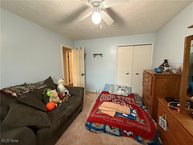 carpeted bedroom with ceiling fan, a closet, and a textured ceiling