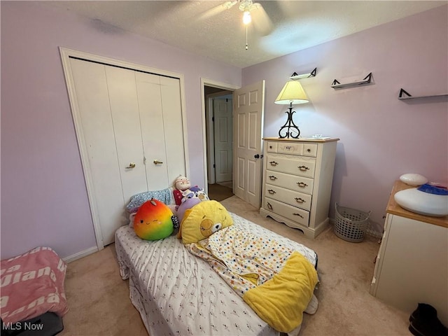 carpeted bedroom with a textured ceiling, ceiling fan, and a closet