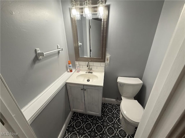 bathroom with vanity, backsplash, and toilet