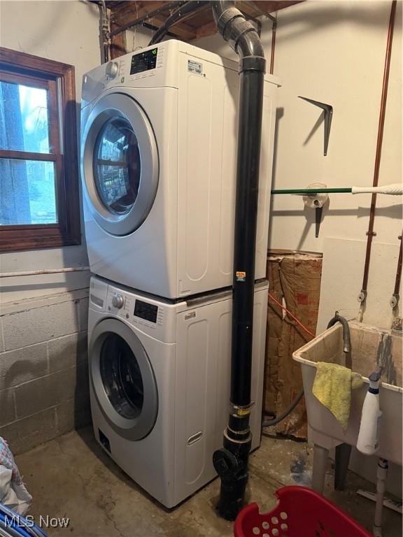 washroom with stacked washer / drying machine and sink