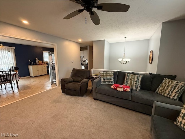 carpeted living room with ceiling fan with notable chandelier and a textured ceiling