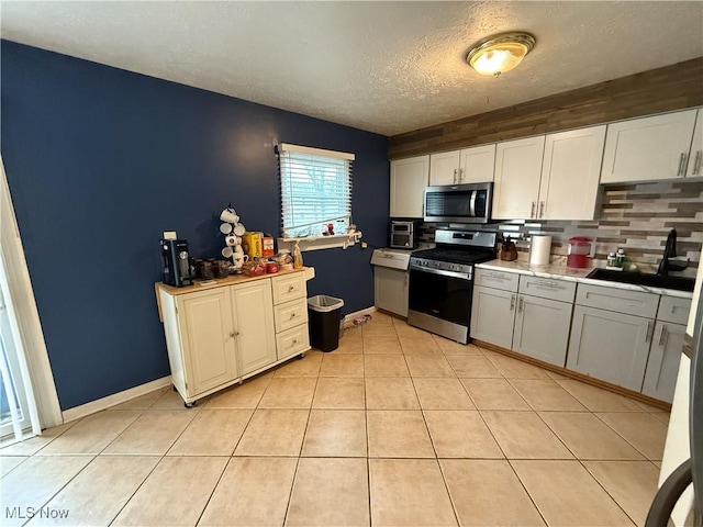 kitchen featuring white cabinetry, appliances with stainless steel finishes, sink, and light tile patterned flooring