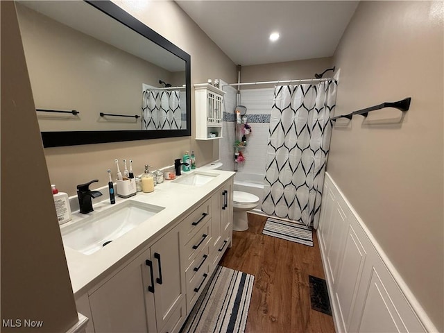 full bathroom with hardwood / wood-style flooring, vanity, shower / bath combination with curtain, and toilet