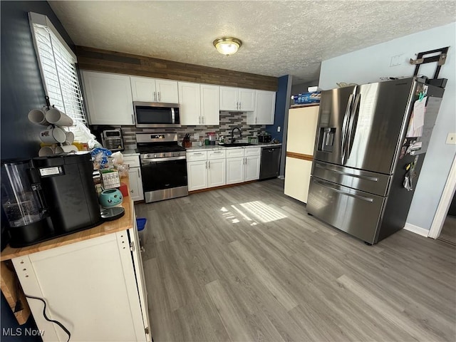 kitchen with hardwood / wood-style flooring, appliances with stainless steel finishes, sink, and white cabinets