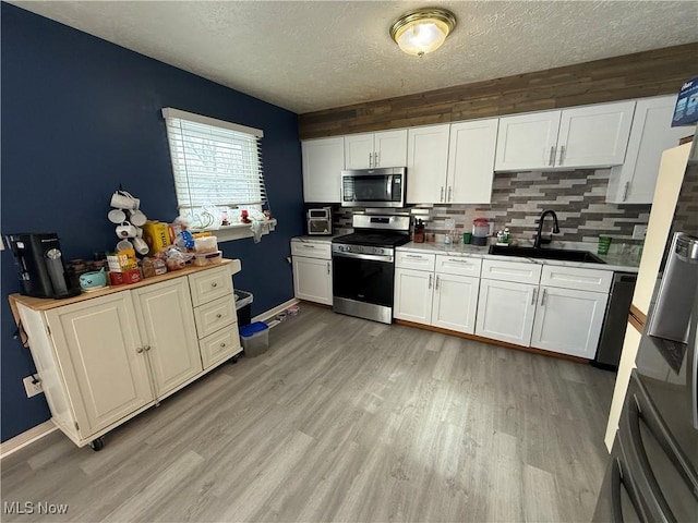 kitchen featuring sink, light wood-type flooring, white cabinets, and appliances with stainless steel finishes