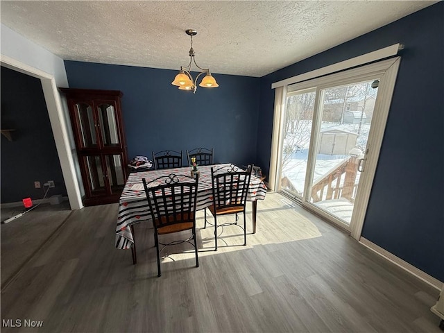 dining room with an inviting chandelier, hardwood / wood-style floors, and a textured ceiling