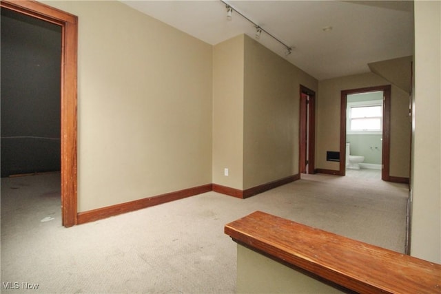 hallway featuring light carpet and track lighting