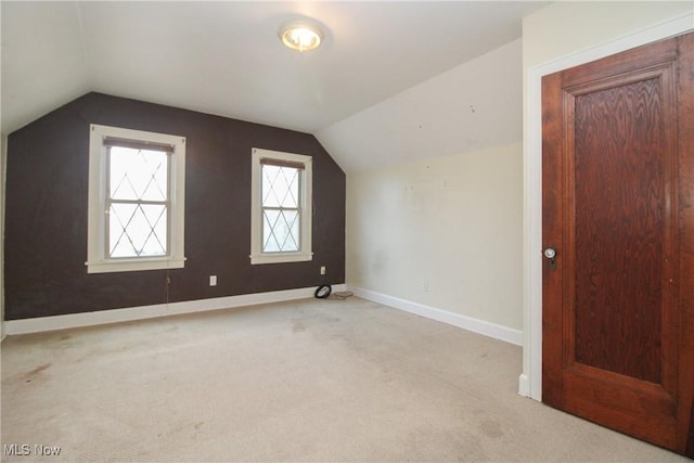 bonus room with vaulted ceiling and light carpet