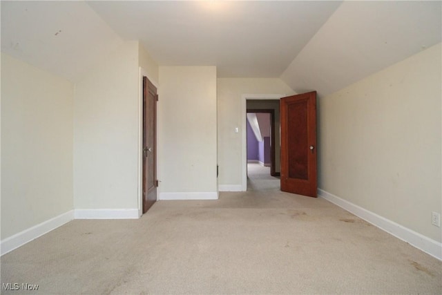 carpeted spare room with lofted ceiling