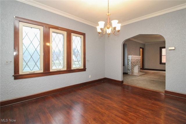 spare room featuring crown molding, dark wood-type flooring, and a notable chandelier