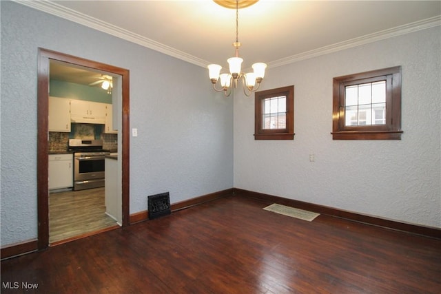 spare room featuring dark wood-type flooring, crown molding, and an inviting chandelier