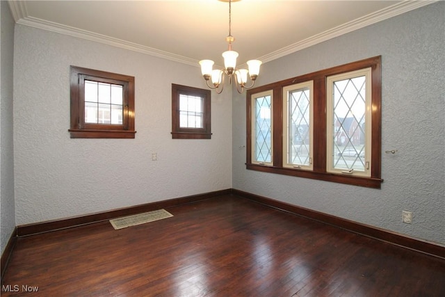 spare room featuring crown molding, dark hardwood / wood-style flooring, and a chandelier