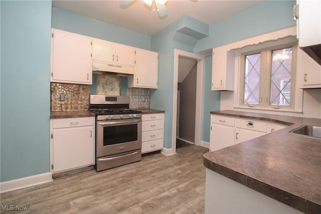 kitchen with stainless steel gas stove, white cabinetry, light hardwood / wood-style flooring, and decorative backsplash