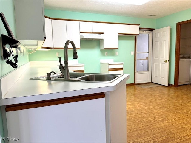 kitchen featuring white cabinetry, separate washer and dryer, sink, light hardwood / wood-style floors, and a textured ceiling