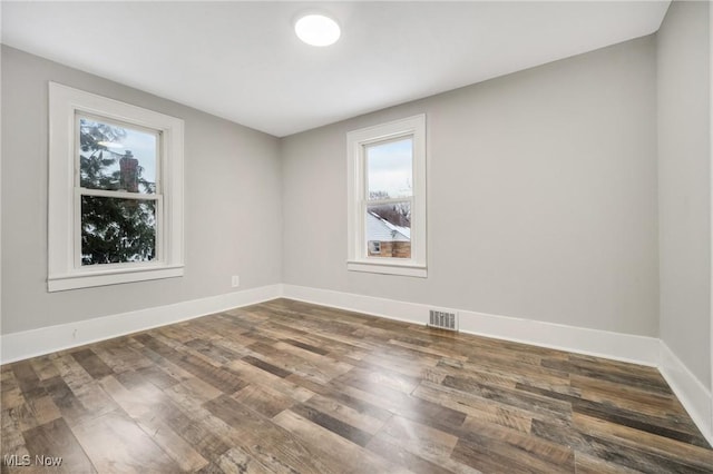 spare room with visible vents, baseboards, and wood finished floors