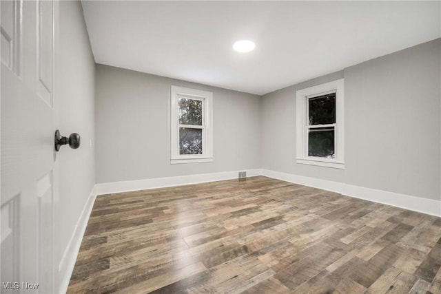 unfurnished room featuring visible vents, baseboards, and wood finished floors