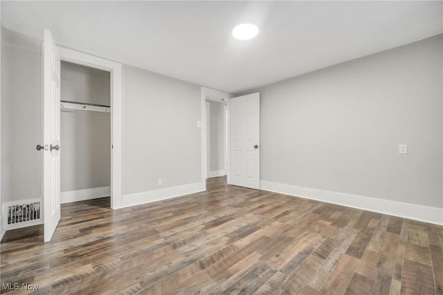 unfurnished bedroom featuring baseboards, visible vents, and wood finished floors